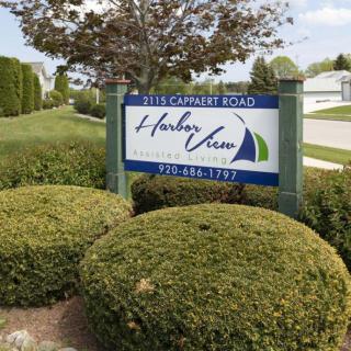 A scenic view featuring a sign for 'Harbor View' surrounded by lush greenery and trees.