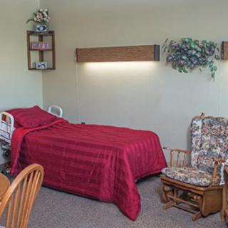 A simple bedroom with red bedding and a floral rocking chair.
