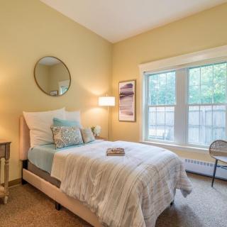 A cozy bedroom with a bed, mirror, and large window.