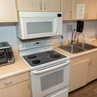 A modern kitchen setup featuring an oven with a built-in stovetop, a microwave above the counter, and a sink.