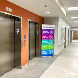 Elevators located in a hospital corridor with informational signage.