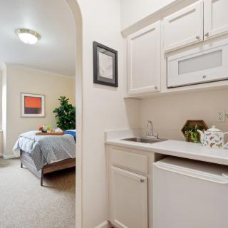 A cozy studio apartment featuring a bedroom and a compact kitchenette with minimalist decor.