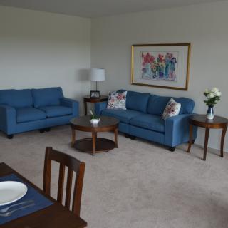 A cozy living room with blue sofas and a dining area.