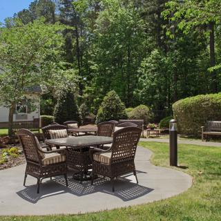 A serene garden patio with wicker furniture surrounded by greenery.