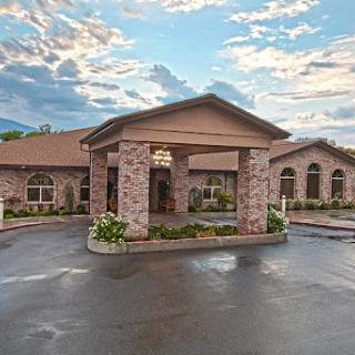An inviting entrance to a residential building featuring attractive landscaping and a cloudy sky.