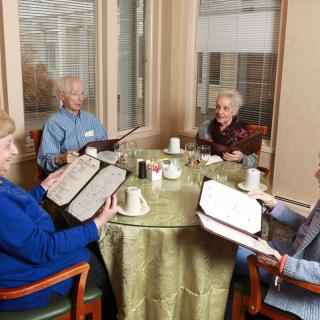 A group of seniors enjoying a meal together at a restaurant, looking at menus.