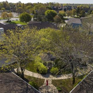 An aerial view of a suburban neighborhood featuring a gazebo surrounded by trees and pathways.