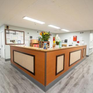 A tidy reception desk with flowers and office supplies.
