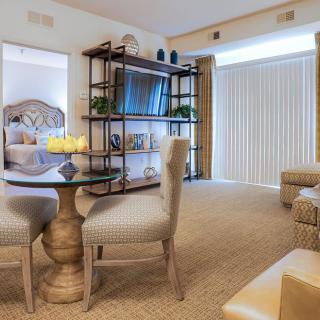 A cozy living room with a dining table, comfortable seating, and a television on shelves.