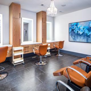 A modern salon interior with stylish hairdressing chairs, mirrors, and a decorative chandelier.