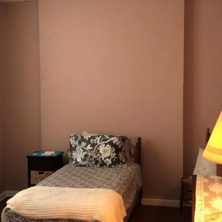 A cozy bedroom with a single bed, nightstand, and lamp.