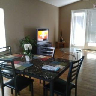 A cozy dining area with a table set, chairs, and a television in a well-lit room.