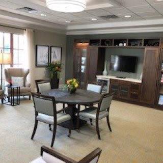 A well-appointed living room featuring a dining table with chairs, a wall-mounted television, and elegant decor.