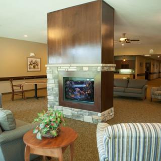 A cozy living room interior featuring a central fireplace surrounded by comfortable seating.