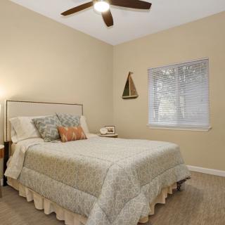 A cozy bedroom with a comfortable bed, ceiling fan, and soft lighting.