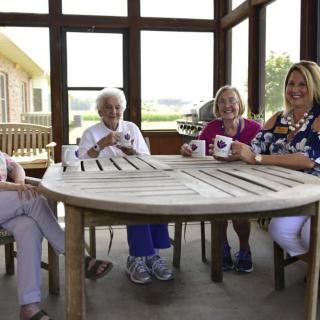 A group of four people enjoying coffee together on a porch.