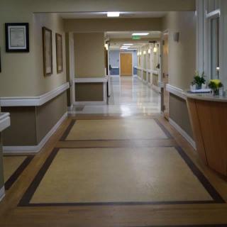 An empty hospital corridor with clean floors and lighting.
