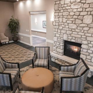 A cozy seating area featuring a stone fireplace and arranged chairs in a warmly lit room.