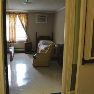 A simple bedroom with a bed, chair, and window curtains.
