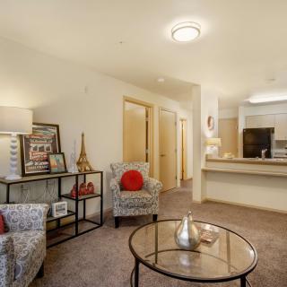 A cozy living room with stylish furniture and warm lighting, featuring a small table and decorative elements.