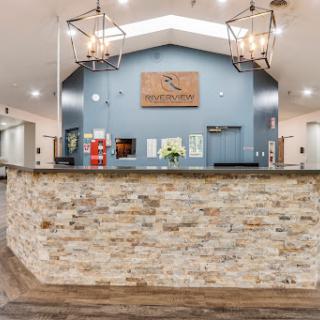 A stylish and welcoming lobby featuring modern design elements, including a stone reception desk and elegant chandeliers.