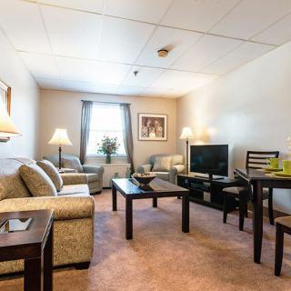 A cozy living room with a sofa, coffee table, TV, and dining area.