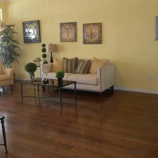 A cozy living room with a sofa, hardwood floors, and decorative artwork on the wall.