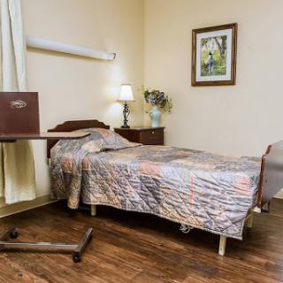 A cozy room featuring a single bed with a patterned quilt, accompanied by a side table and decorative elements.