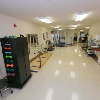 A spacious rehabilitation center equipped with exercise equipment and therapy stations.