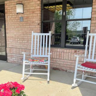 A cozy outdoor seating area featuring rocking chairs and blooming flowers, inviting relaxation on a sunny day.