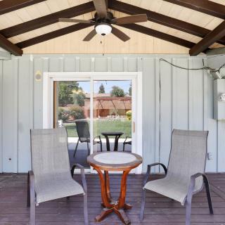 A cozy patio setup with chairs and a table under a covered area featuring a ceiling fan.