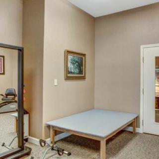 A small exercise room with a table, mirror, and artwork on the wall.