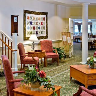 A cozy living room with traditional decor, featuring comfortable chairs and a table adorned with plants.