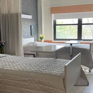 A peaceful hospital room with two beds and a window letting in natural light.