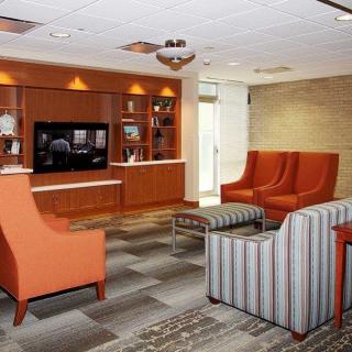 A modern lobby seating area with comfortable chairs and a television.