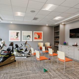 A modern gym featuring stationary bikes, chairs, and artwork on the walls.
