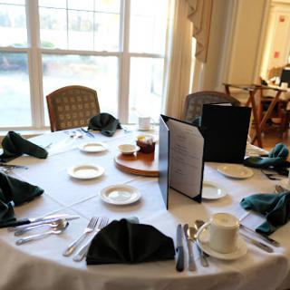 A beautifully arranged dining table with green napkins, plates, cutlery, and a menu in an elegant setting.