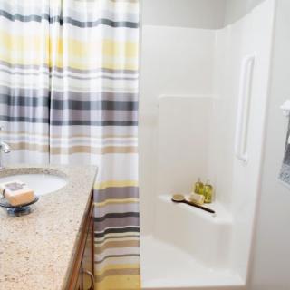 A modern bathroom with a striped shower curtain, a sink with a granite countertop, and various toiletries.