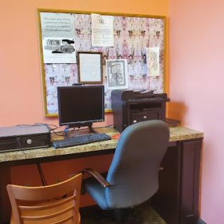 A cozy workspace featuring a computer, printer, and bulletin board.