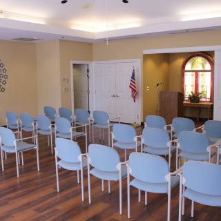 An empty meeting room with rows of chairs arranged for a conference.