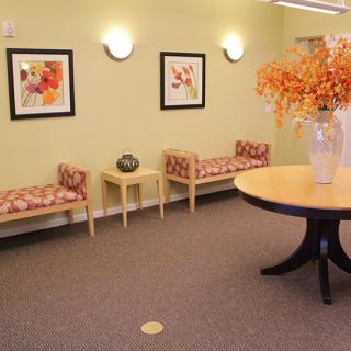 A cozy waiting room with benches, decorative artwork, and a table with a floral arrangement.