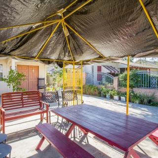 A sunny outdoor patio area with a large umbrella shading a table and bench seating.