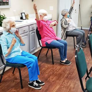 Seniors participating in a chair exercise class together indoors.