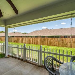 A cozy covered patio overlooking a fenced backyard with a lush green lawn.