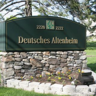 A sign for Deutsches Altenheim set against a natural landscape.