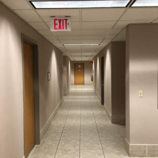 A view of a well-lit hallway featuring multiple doors and an exit sign.