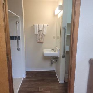 An accessible bathroom featuring a sink with handrails, towels, and a shower area.