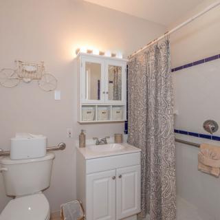 A clean and tidy bathroom featuring a shower with a patterned curtain, a white vanity with a mirror cabinet above, and neatly arranged towels.
