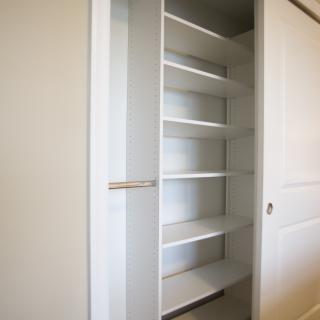 An empty closet with several white shelves for storage and organization.