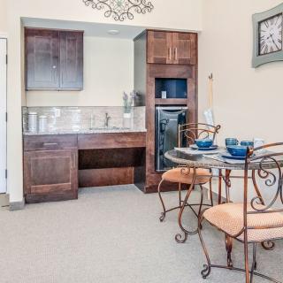 A cozy kitchen and dining area featuring wooden cabinets, a small table with chairs, and elegant decor.